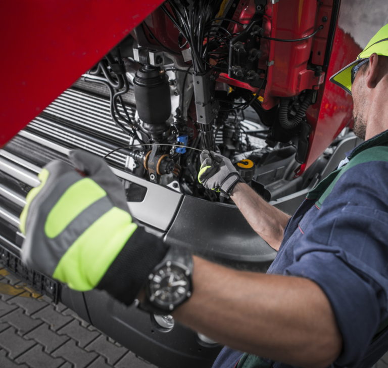 En la imagen se muestra un hombre dando mantenimiento a un camión