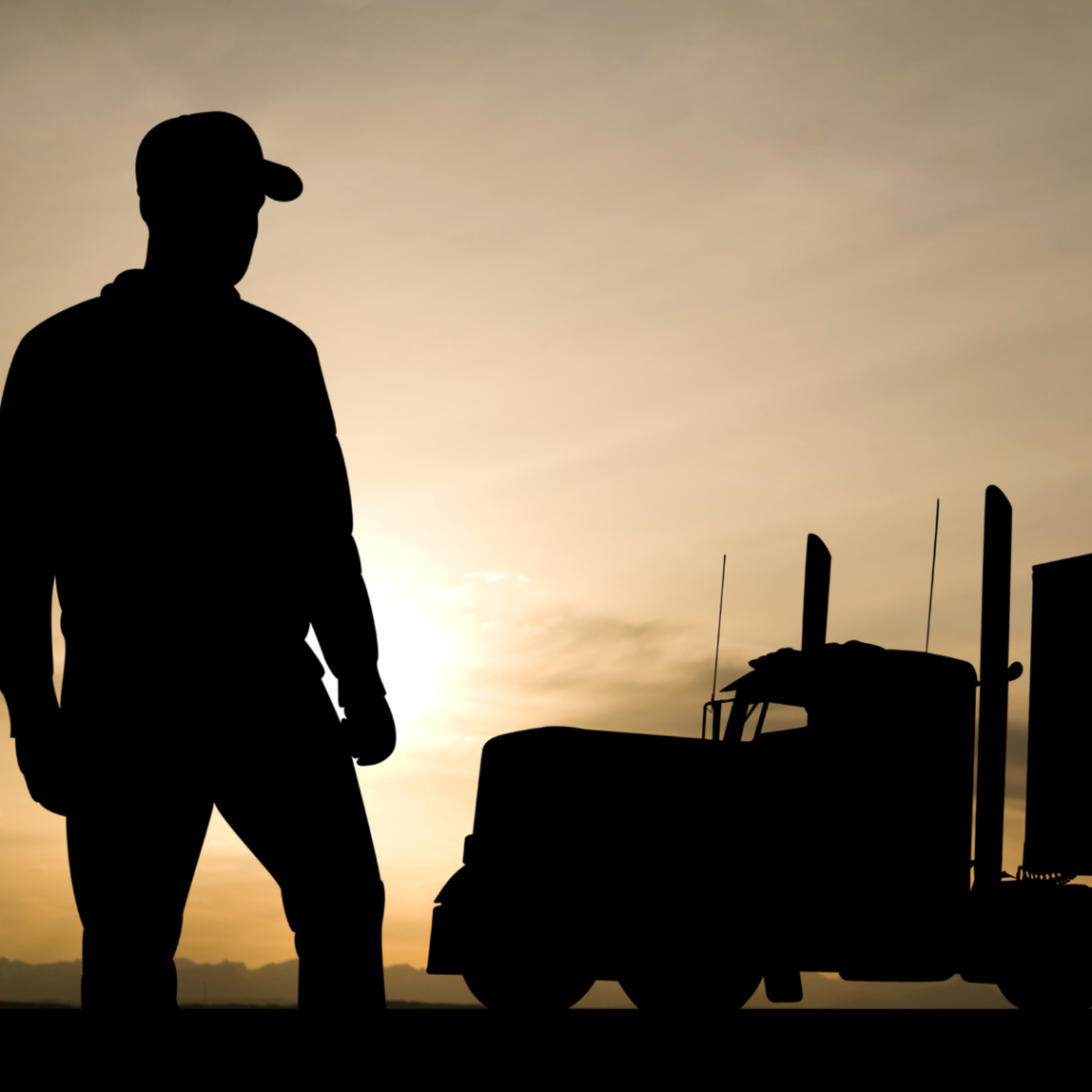 En la imagen se observa la figura de un camionero y un camión contraluz