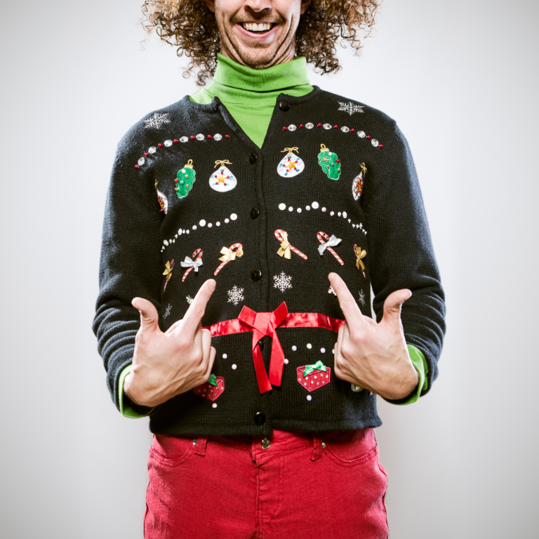 En la imagen se observa un homre sonriendo con un suéter navideño