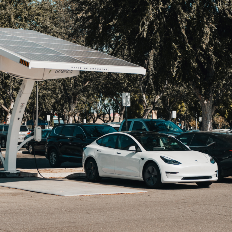 En la imagen se muestra un vehículo blanco de la marca Tesla, en una estación de recarga.