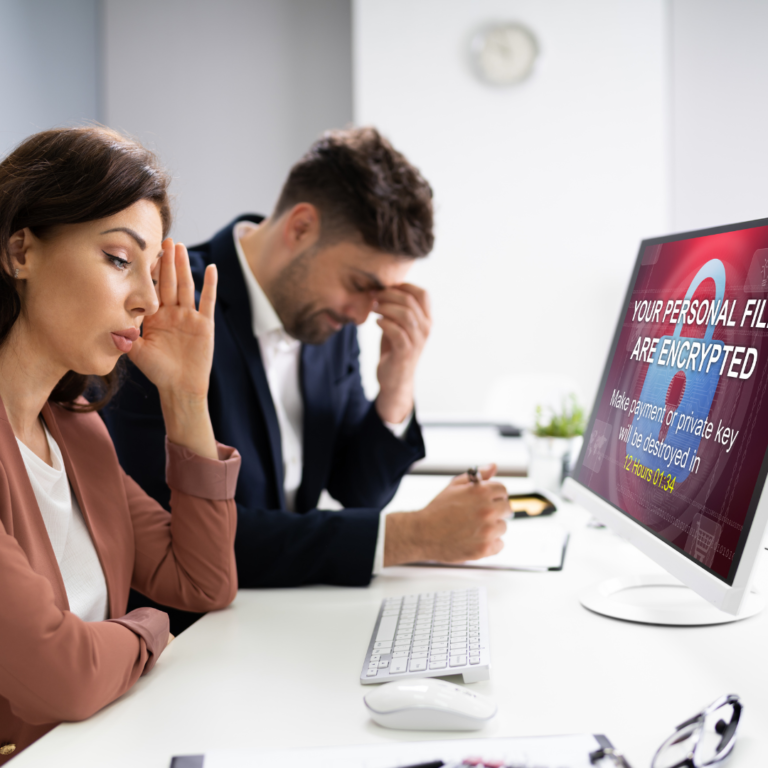 En la imagen se muestran dos personas con expresión de enfado, frente a una computadora que indica un ciber ataque