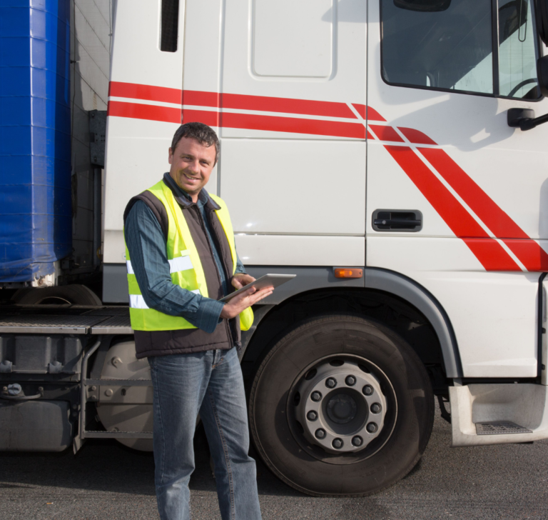 En la imagen se muestra un hombre sonriendo frente a un camión