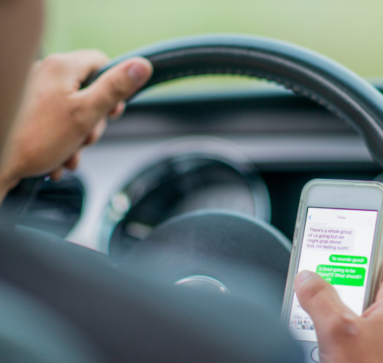 En la imagen se muestra una persona conduciendo con el móvil en mano