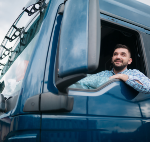 En la imagen se muestra un hombre sonriendo dentro de un camión