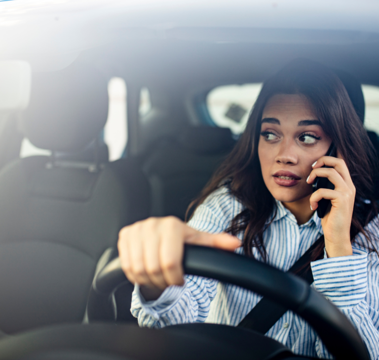 En la imagen se muestra una mujer conduciendo mientras utiliza el teléfono