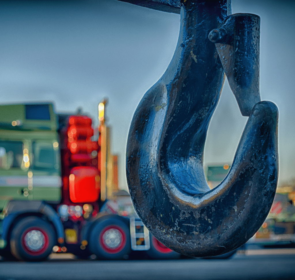 En la imagen se muestra un gancho de grúa con un camión de fondo