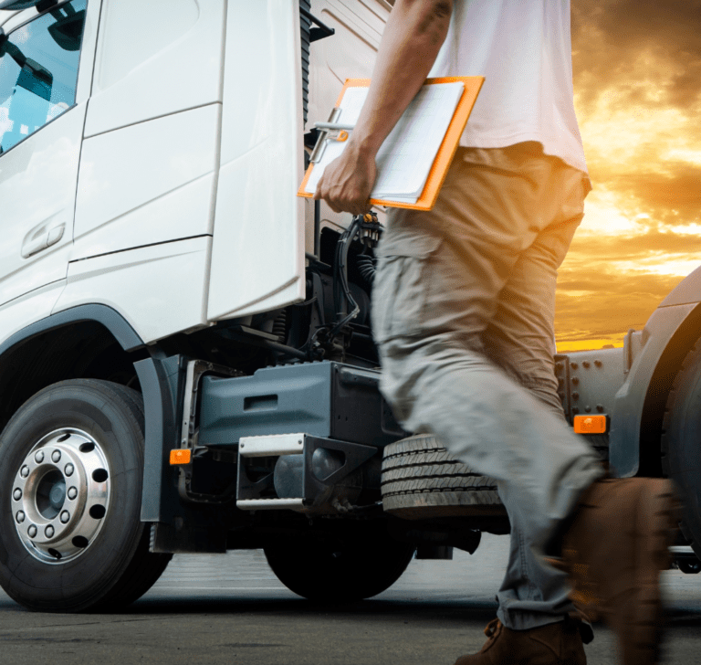 En la imagen se muestra un camionero inspeccionando un camión